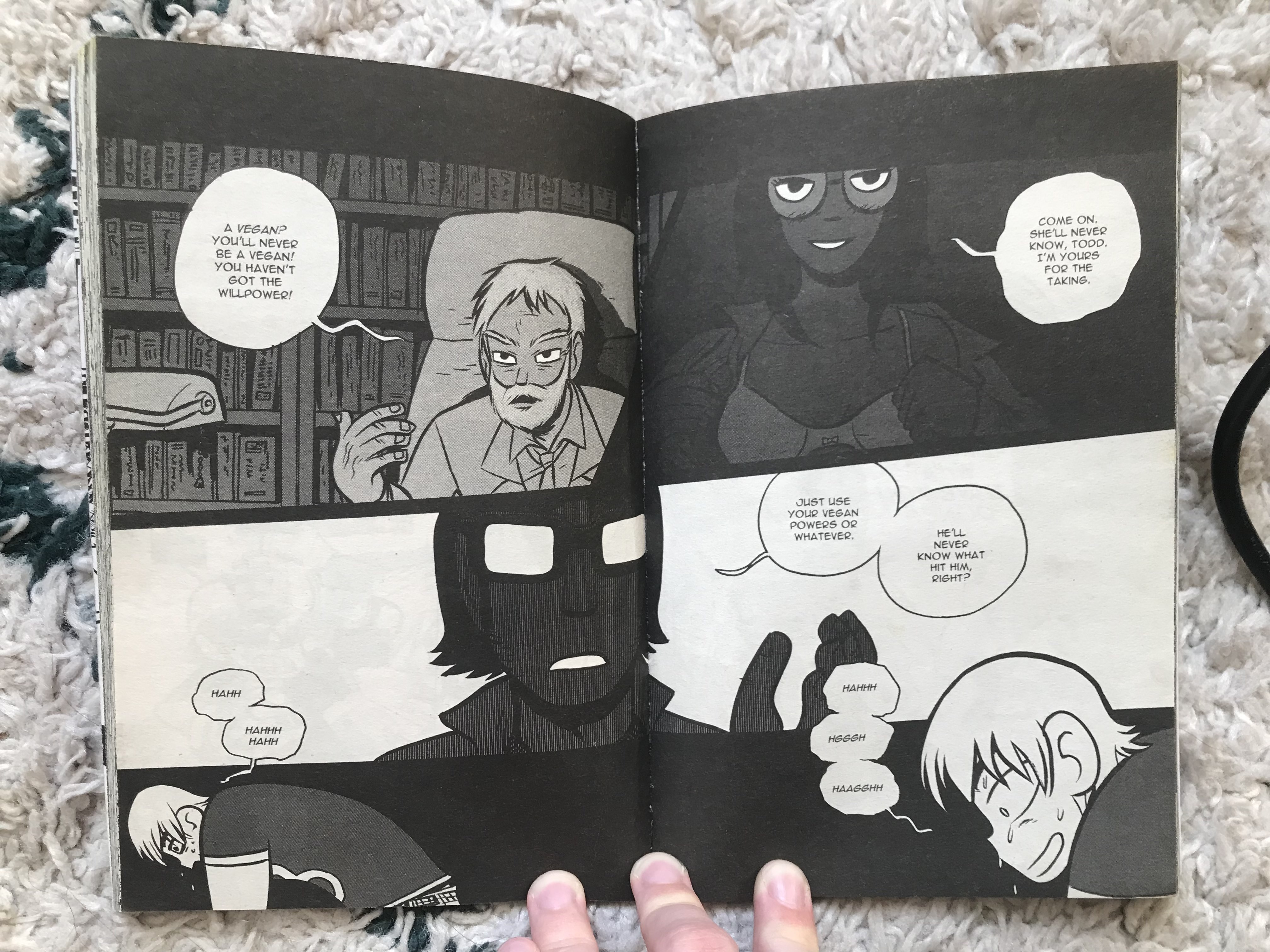 A photo of a black and white double spread from Scott Pilgrim, showing a more sparse panel layout that crosses beneath both pages.