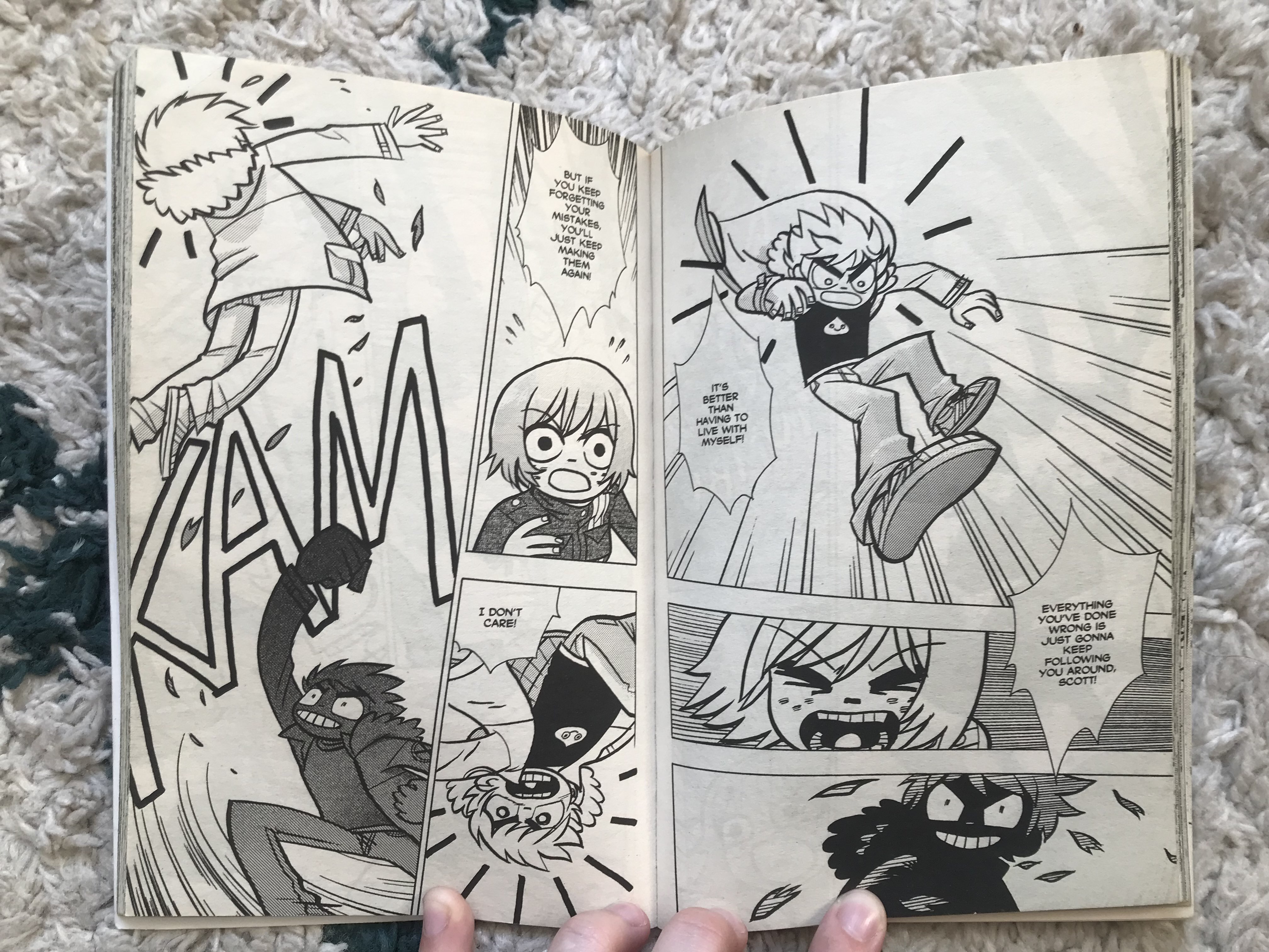 A photo of two black and white pages from Scott Pilgrim, showing Scott trying to fight NegaScott, and Kim explaining how he can't defeat NegaScott because he needs to come to terms with his mistakes.