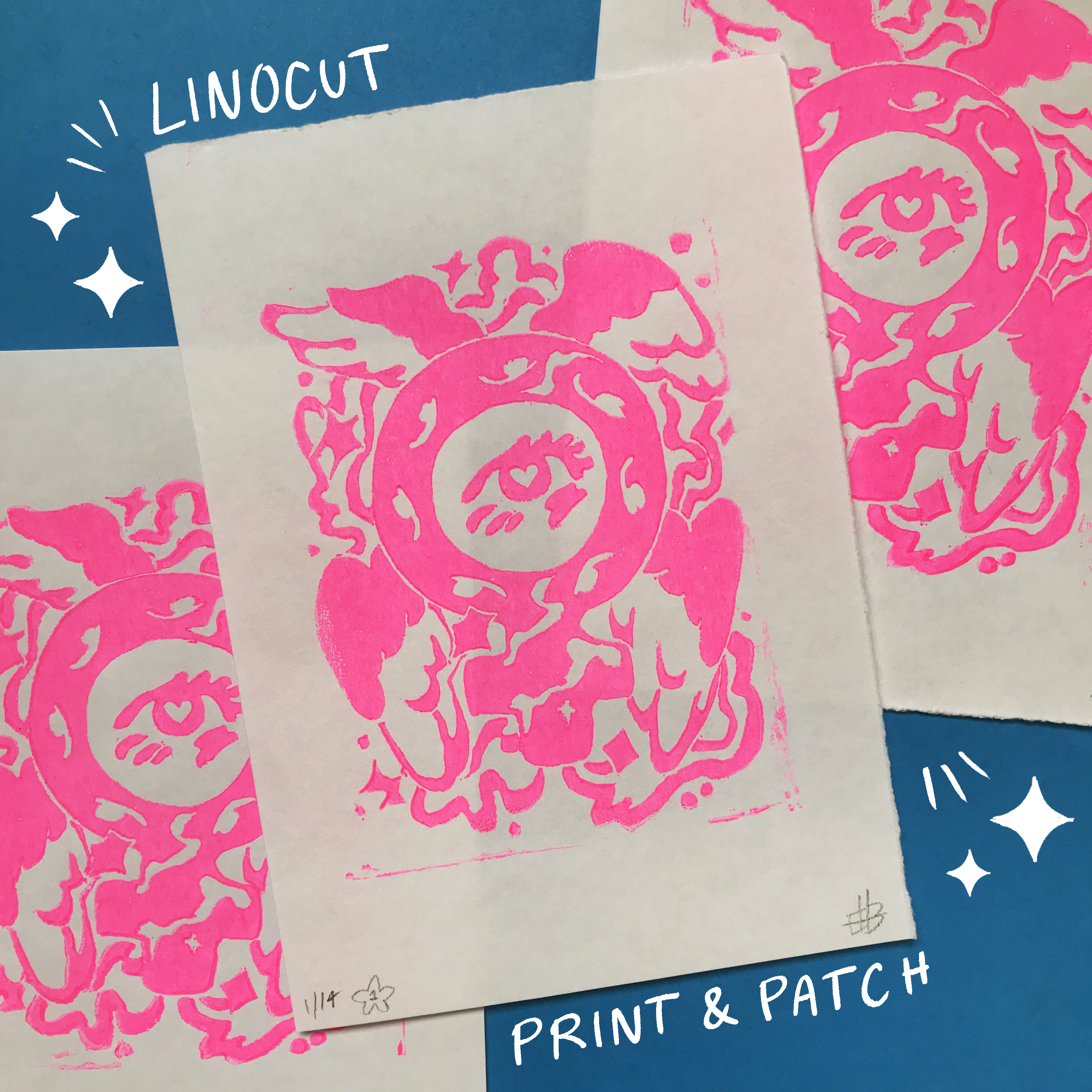 A product photo of a pile of linocuts in fluorescent pink on white paper against a blue background. The prints are of a venus sign stylised as a wheel-like angel, with wings coming out of it, eyes around the circular portion and sparkles and stars in the background.